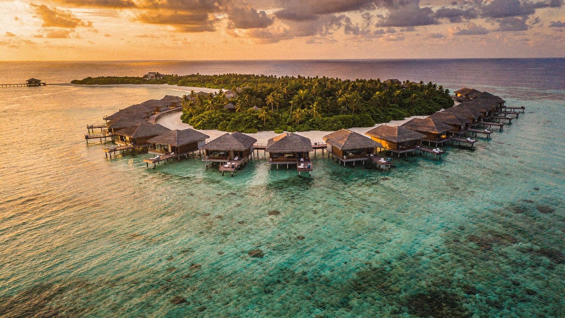 Overwater villas and turquoise lagoon at a Maldives resort at sunset